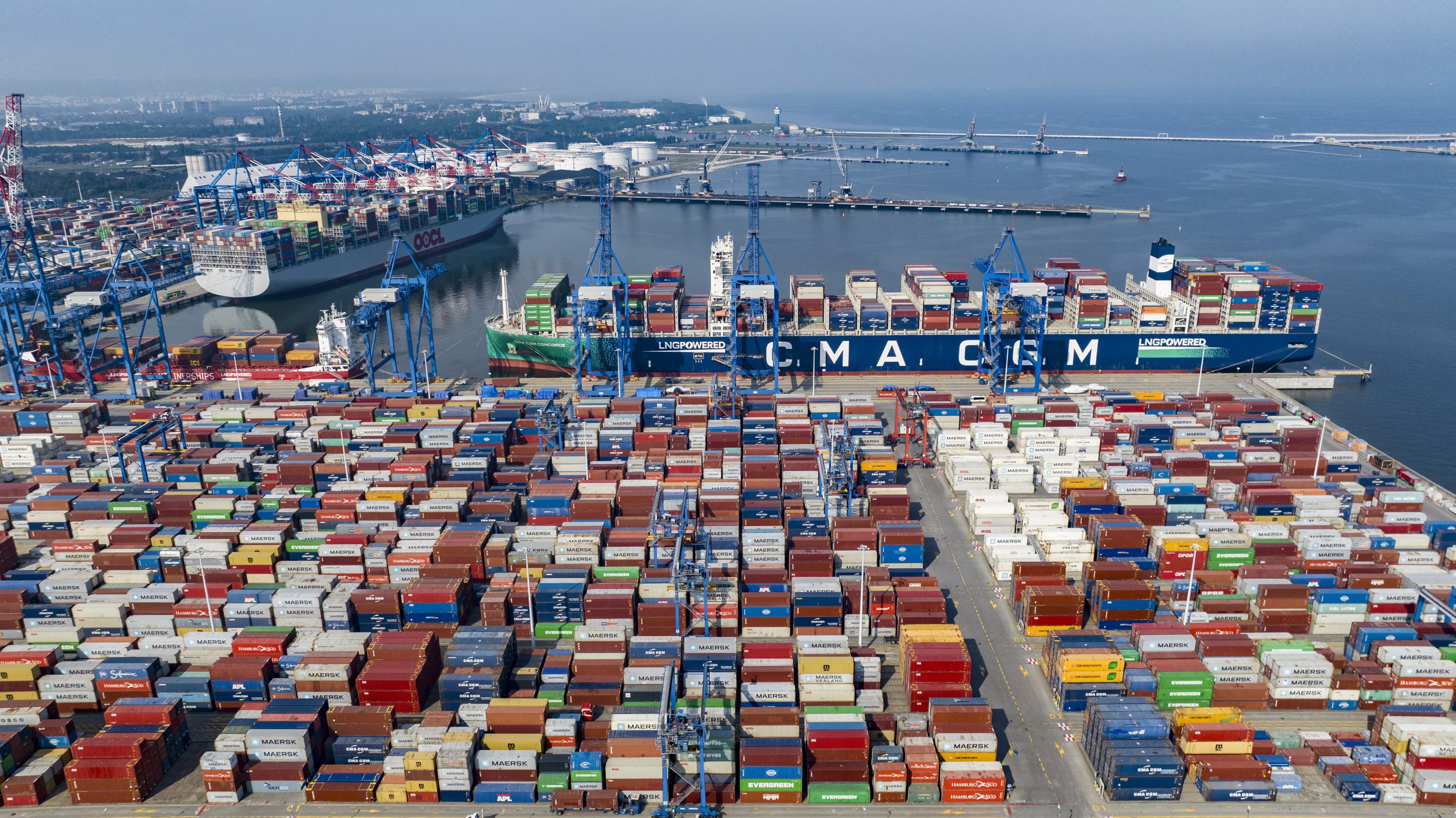 Aerial view of a busy container terminal with massive ships and stacked cargo containers.
